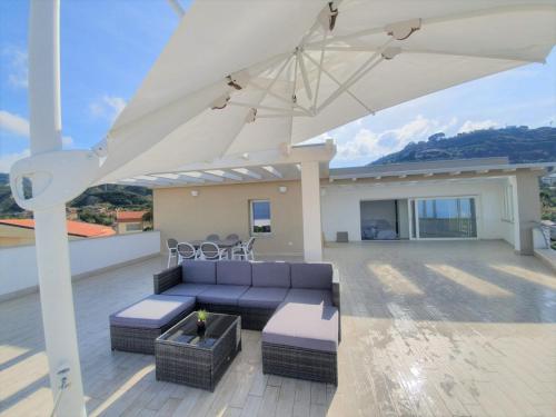 a patio with a couch and an umbrella at Sapphire Penthouse in Tropea