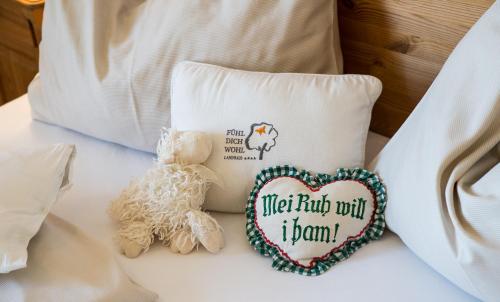 a stuffed teddy bear sitting on a bed next to a pillow at FerienAppartments Landhaus FühlDichWohl in Fehring