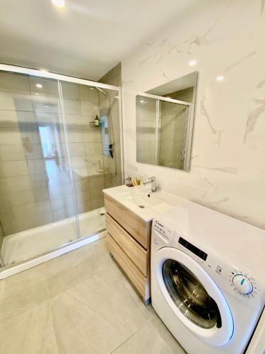 a washing machine in a bathroom with a shower at Lowenva beach apartment in Canet de Berenguer