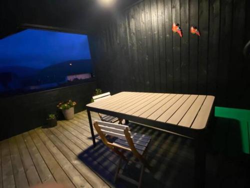 a table and a chair on a deck with a window at Nice one-story house in Suduroy in Tvøroyri