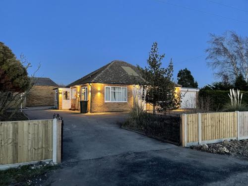 a house with a fence in front of a driveway at 2 bedroom detached bungalow with Hot Tub and secure garden and parking - Pet Friendly on 7 acres of land in Boston