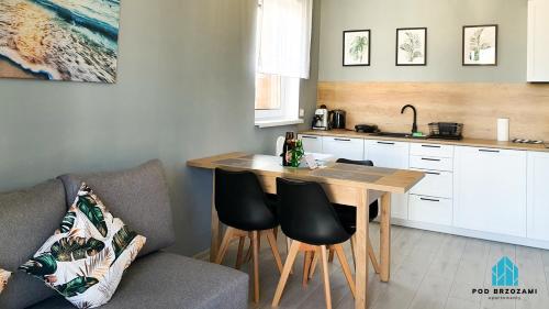 een keuken met een houten tafel en stoelen in een kamer bij Pod Brzozami Apartamenty Górna in Ustronie Morskie