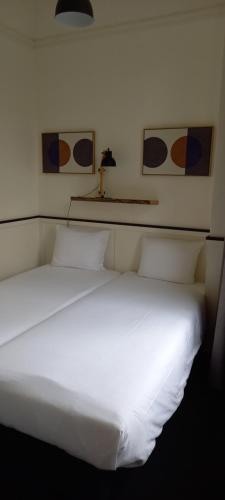 a white bed with two pillows in a room at Stad & Strandhotel Elisabeth in Vlissingen