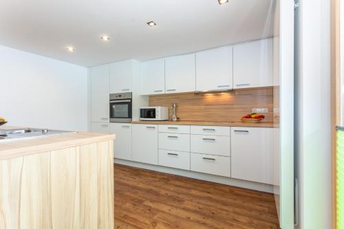 a kitchen with white cabinets and a counter top at lechner living apartments in Wald im Pinzgau