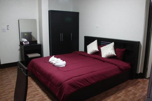 a bedroom with a red bed with towels on it at Bansappoori in Lamphun