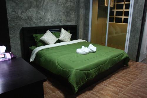 a bedroom with a green bed with white shoes on it at Bansappoori in Lamphun