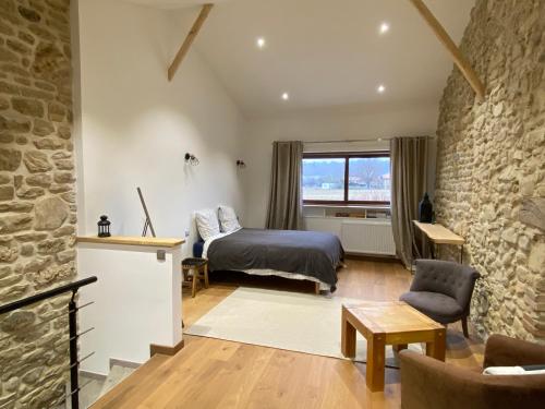 1 dormitorio con cama y pared de piedra en Gites&chambres d hôtes Les granges du Fournel en Saint-Lattier