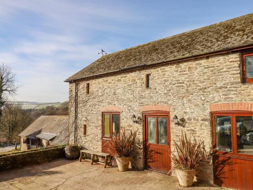 a stone building with red doors and potted plants at Bradley Stables in Minehead