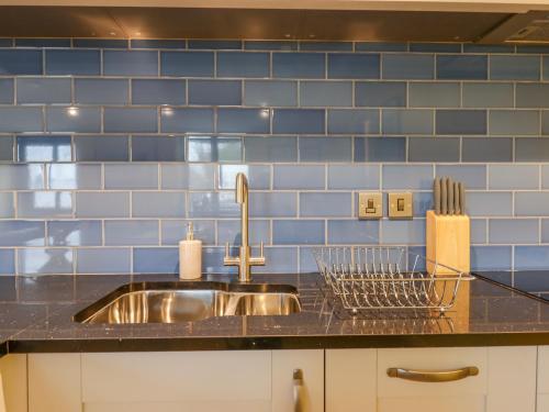a kitchen with a sink and a blue tiled wall at Bradley Stables in Minehead