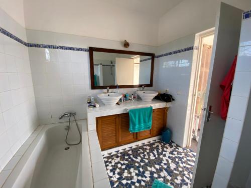 uma casa de banho com 2 lavatórios, uma banheira e um espelho. em Villa avec piscine entre plage et Siné Saloum em Palmarin