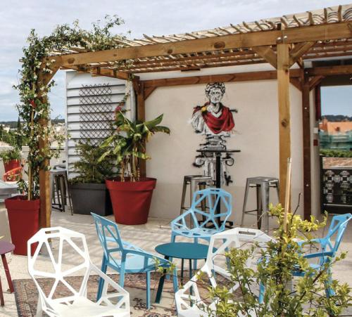 a patio with chairs and a painting on the wall at Hostel Vertigo Nîmes Gare Centre in Nîmes