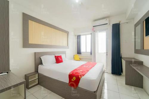 a bedroom with a bed with a red blanket on it at RedLiving Apartemen Riverview Residence - TOHA Room Tower Mahakam in Tegalgede