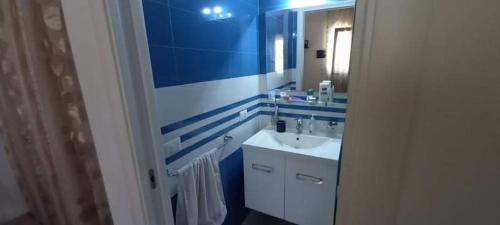 een blauwe en witte badkamer met een wastafel en een spiegel bij Appartamento Porto Cesareo in Porto Cesareo