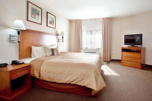 ニューアイビーリアにあるCandlewood Suites New Iberia, an IHG Hotelのベッド1台、薄型テレビが備わるホテルルームです。