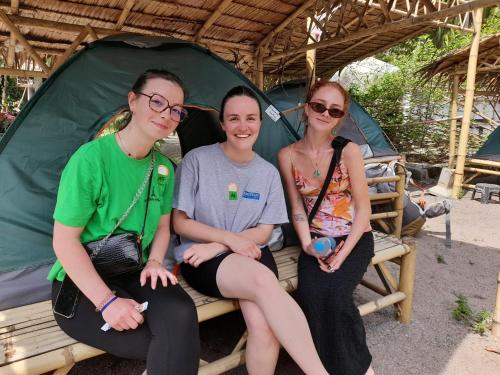 three women sitting on a bench in a tent at Ganja Gardens Camping in Ban Nua