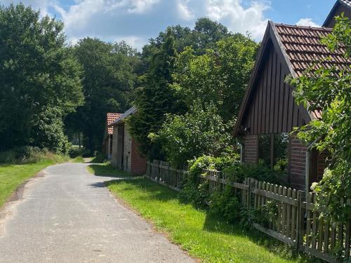 a dirt road next to two houses and a fence at Wunderschöne Ferienwohnung auf dem Bauernhof in Greven