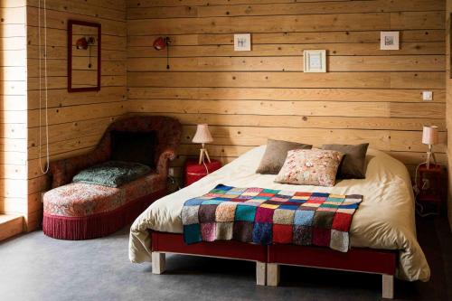 a bedroom with a bed and a chair at Le Vallon d'Armandine, gîte écologique Auvergne in Saint-Hilaire