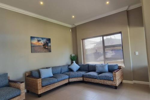 a living room with a blue couch and a window at Luxury Beachhouse Villa II in Wilderness