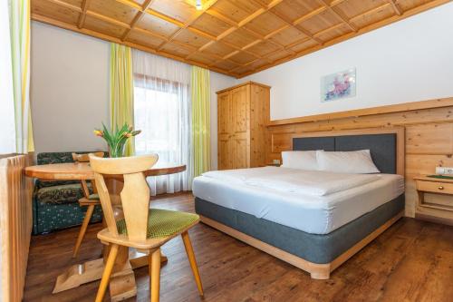 a bedroom with a bed and a desk and a table at lechner living apartments in Wald im Pinzgau