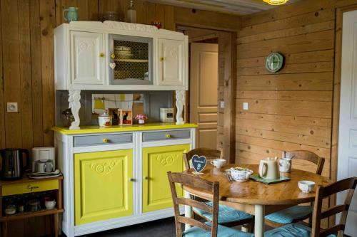 a kitchen with a yellow and white cabinet and a table at Le Vallon d'Armandine, gîte écologique Auvergne in Saint-Hilaire