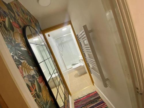 a hallway with a mirror and a bathroom with a sink at Neptune's Nook, Cromer in Cromer