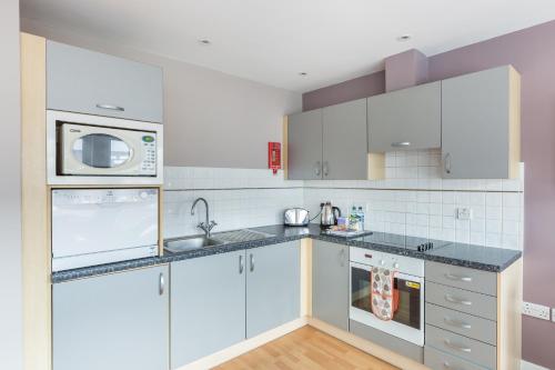 a kitchen with white cabinets and a microwave at House of Fisher - City Wall House in Reading
