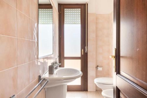 a bathroom with a sink and a toilet and a window at Dimoras Bellissimo Appartamento Centrocittà in Olbia