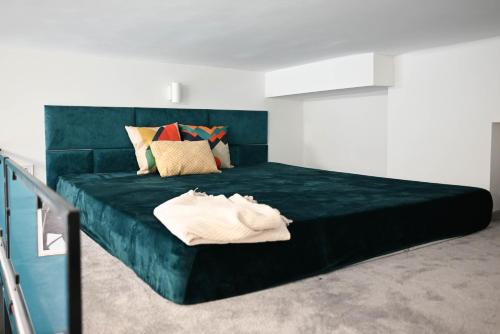 - un lit avec une couverture verte et des oreillers dans l'établissement Petőfi Apartman Pécs, à Pécs
