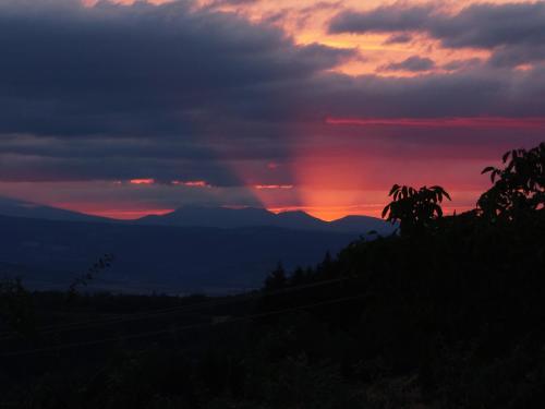 a sunset in the mountains with a rainbow in the sky at Le Vallon d'Armandine, gîte écologique Auvergne in Saint-Hilaire