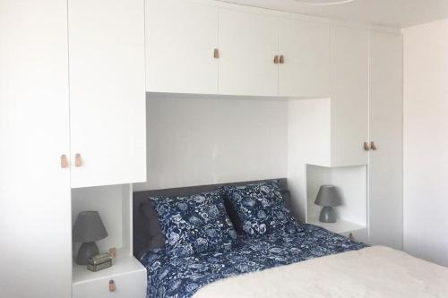 a white bedroom with a bed with blue pillows at Cosy studio flat, great location! in London