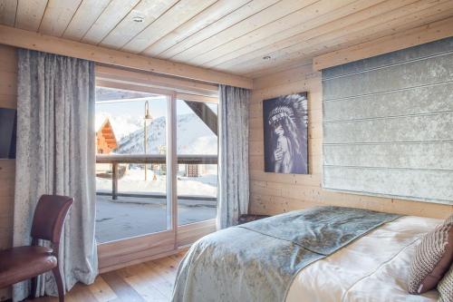 ein Schlafzimmer mit einem Bett und einem großen Fenster in der Unterkunft Chalet Opale in Tignes