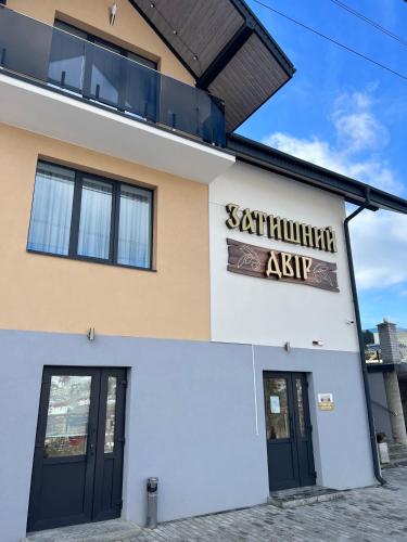 a building with a sign on the side of it at Guest House Zatyshnyi Dvir in Bukovel