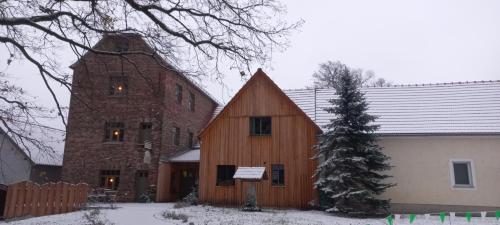 un granero de madera grande en la nieve con un árbol en Wassermühle Förstgen - Eichenzimmer 