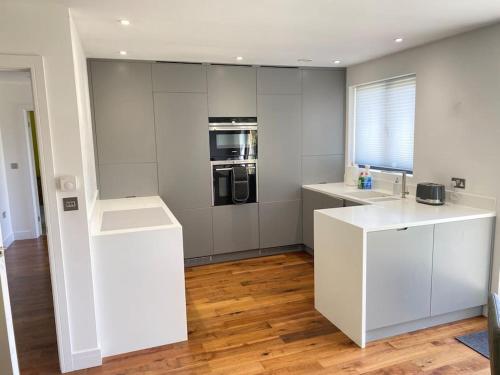 a kitchen with white cabinets and a counter top at Cedar Garden Cottage in East Chinnock