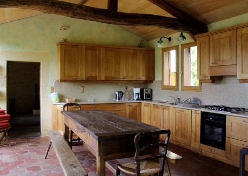 eine Küche mit Holzschränken und einem Holztisch in der Unterkunft Domaine du Fraysse L'Ermitage un coin de paradis in Saint-Cybranet