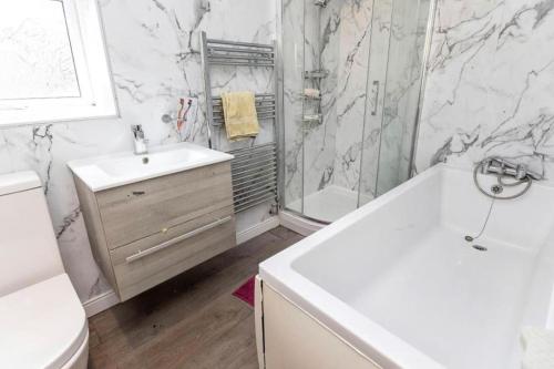 a bathroom with a sink and a tub and a toilet at Onchan House, Beal in Knottingly
