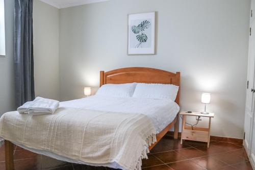 um quarto com uma cama com lençóis brancos e 2 candeeiros em Traditional Portuguese Village House - Casa Martins no 52 em Freiria