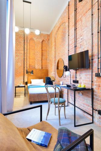a room with a brick wall and a desk with a bed at ARCHE Dwór Uphagena Gdańsk in Gdańsk