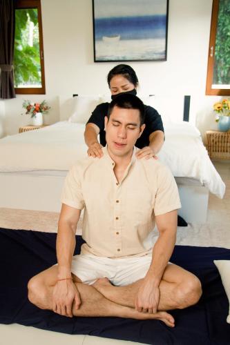 a man sitting on the floor with another man behind him at Maitria Mode Sukhumvit 15 Bangkok - A Chatrium Collection in Bangkok