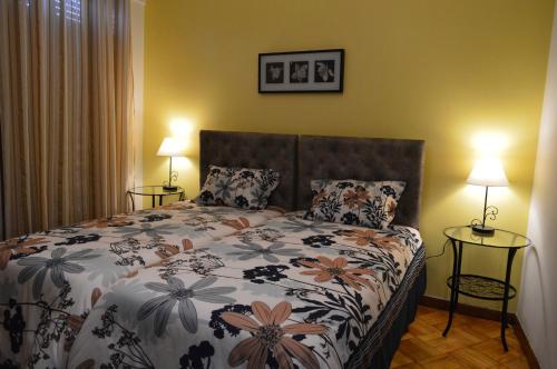 a bedroom with a bed with a floral bedspread and two lamps at Domus Porto Perfeito in Porto