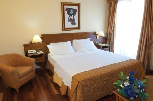 a hotel room with a bed and a chair at Hotel La Bussola in Novara