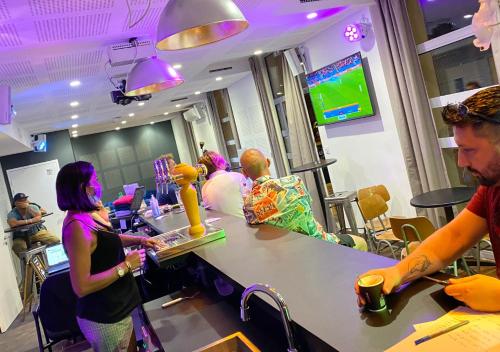 un grupo de personas sentadas en un bar en una barbería en Hostel Vertigo Nîmes Gare Centre en Nimes