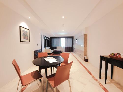 a dining room and living room with a table and chairs at AP Premier Batam in Nagoya