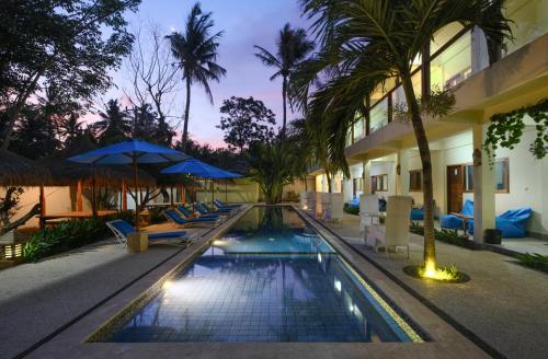 a resort swimming pool with lounge chairs and umbrellas at Trawangan Nirvana in Gili Trawangan