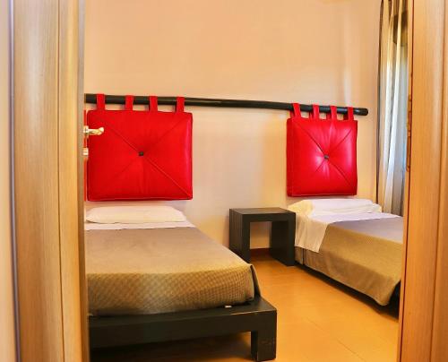 two beds in a small room with red pillows at Aparthotel Isabella in Sciacca