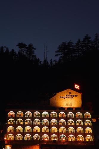 a large building with lights in the night at Shingar Regency in Manāli