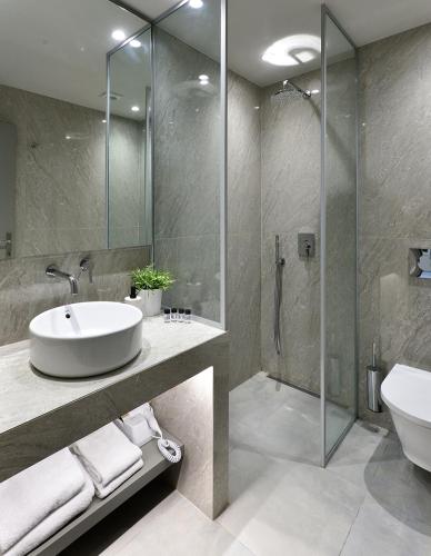 a bathroom with a sink and a glass shower at Le Palace Hotel in Thessaloniki