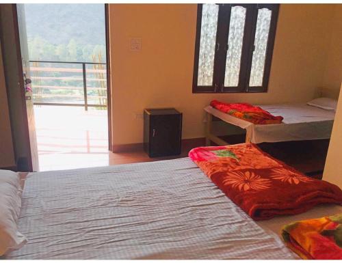 a bedroom with two beds and a large window at Amba Niwas Home Stay, Uttarkashi in Uttarkāshi