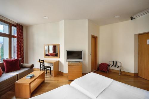 a living room with a couch and a tv at Le Palace Hotel in Thessaloniki