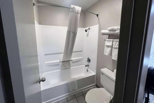 a bathroom with a white tub and a toilet at Days Inn & Suites by Wyndham - Canton First Monday Trade Days in Canton